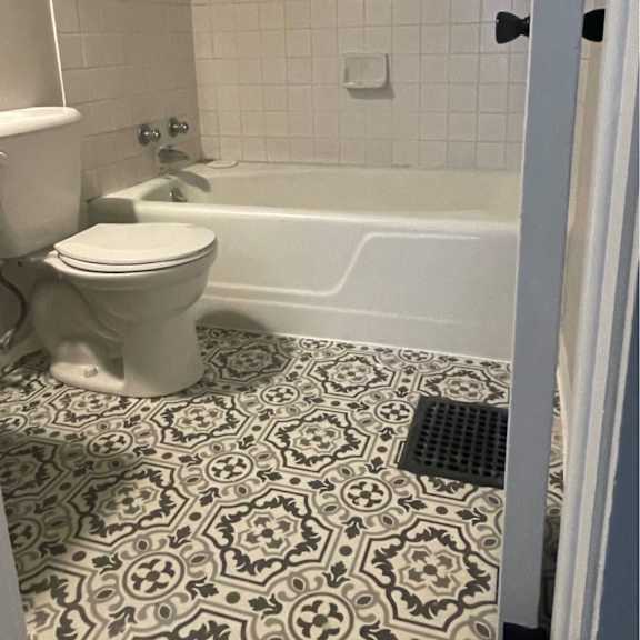a white toilet sits in a bathroom with a black and white floor.