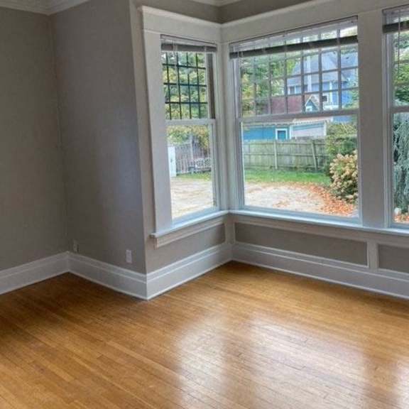 a room with wooden floors and a large window overlooking a garden.
