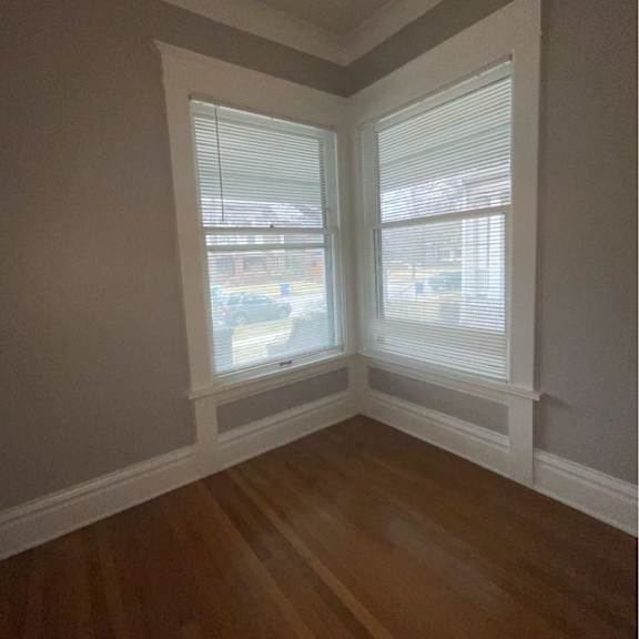a room with two windows and wooden floors.