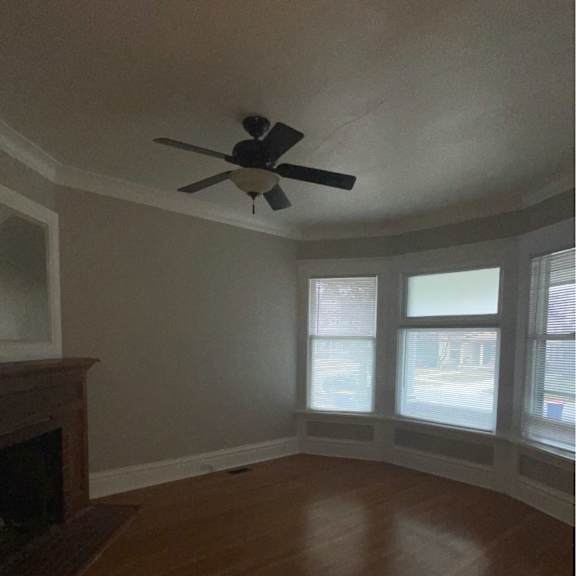 a room with a ceiling fan and a fireplace.