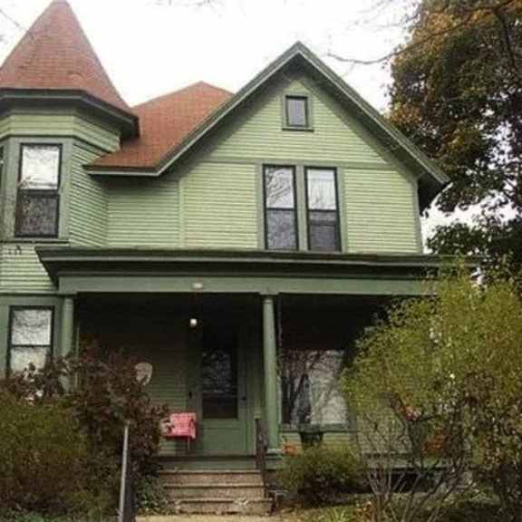 a green house with a red roof and a porch.