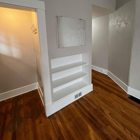a white door with a white frame is open to a room with a wooden floor.