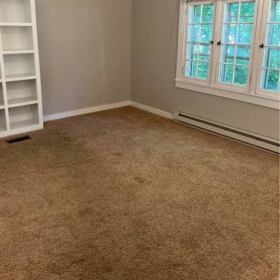 a room with a carpeted floor and a window with blinds.