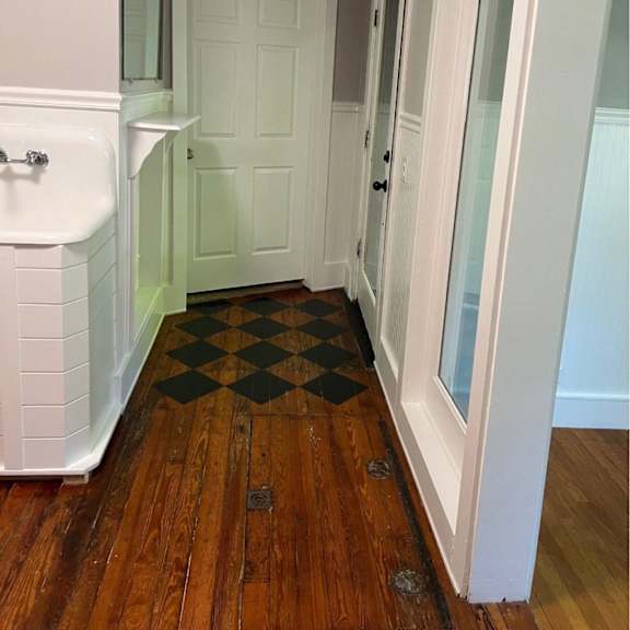 a white door is in a room with a wooden floor.