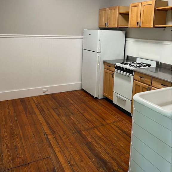 a kitchen with a white refrigerator, stove, and wooden cabinets.