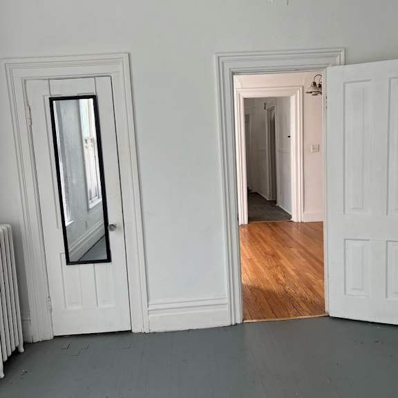 a white door with a mirror on the left side and a white wall.