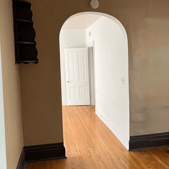 a hallway with a white door and a black shelf.