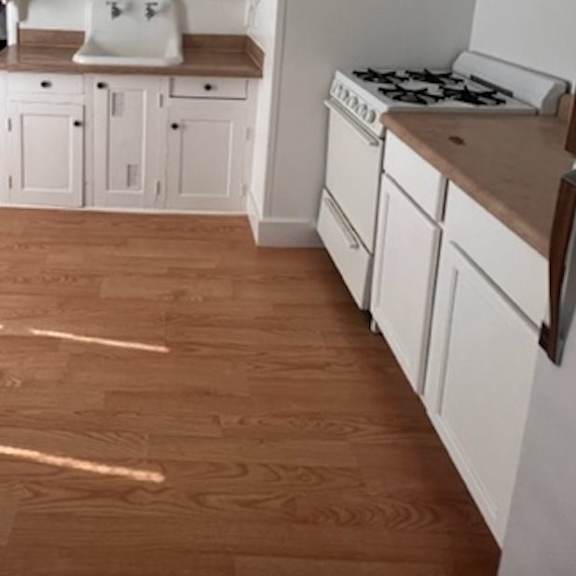 a kitchen with white cabinets and a wooden floor.