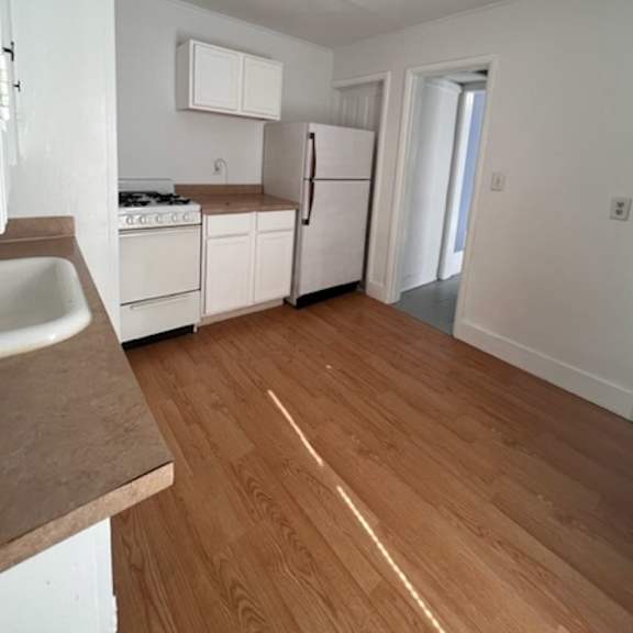 a kitchen with white appliances and wooden floors.