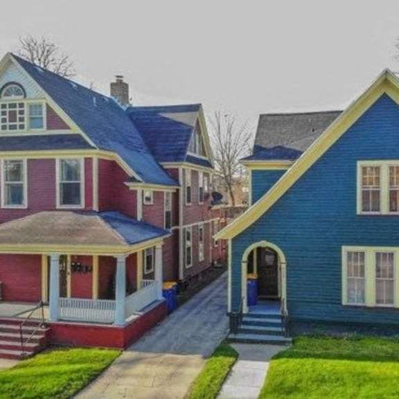 a blue house with a red house in the background.