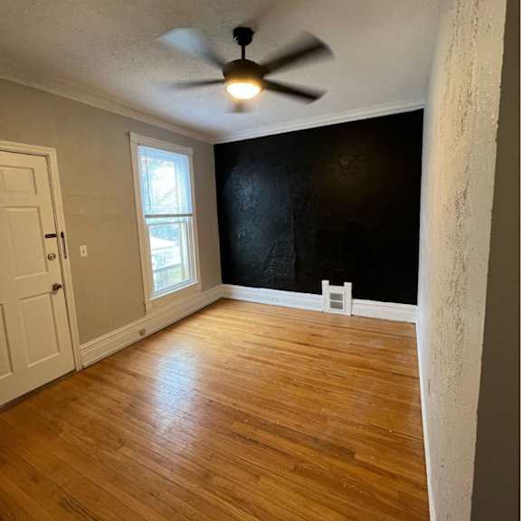 a room with a ceiling fan and wooden flooring.