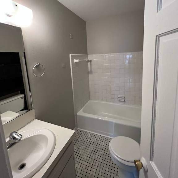a white toilet with a white sink and a white bathtub in a bathroom.