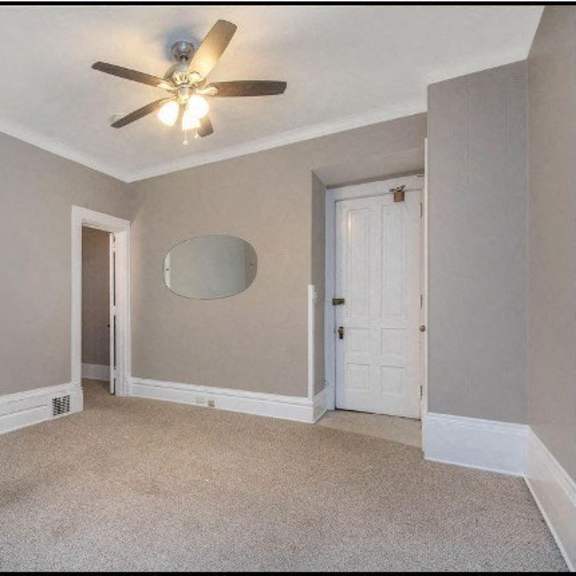 a room with a ceiling fan and a round mirror on the wall.