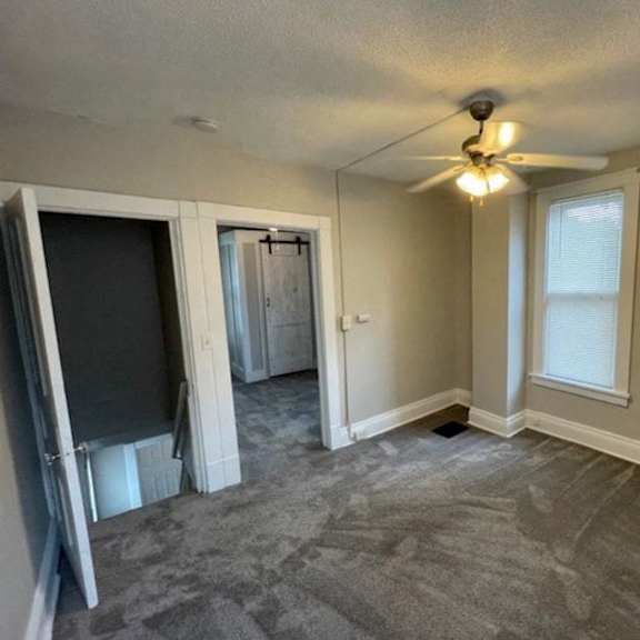 a room with a ceiling fan and a door leading to another room.