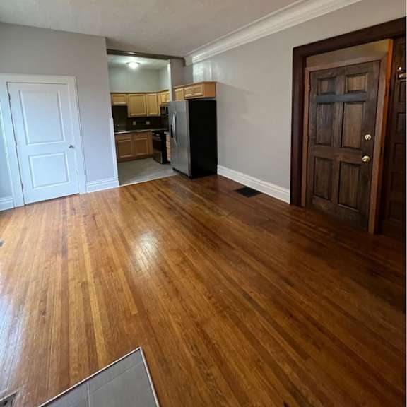 a kitchen with a white door and a wooden floor.