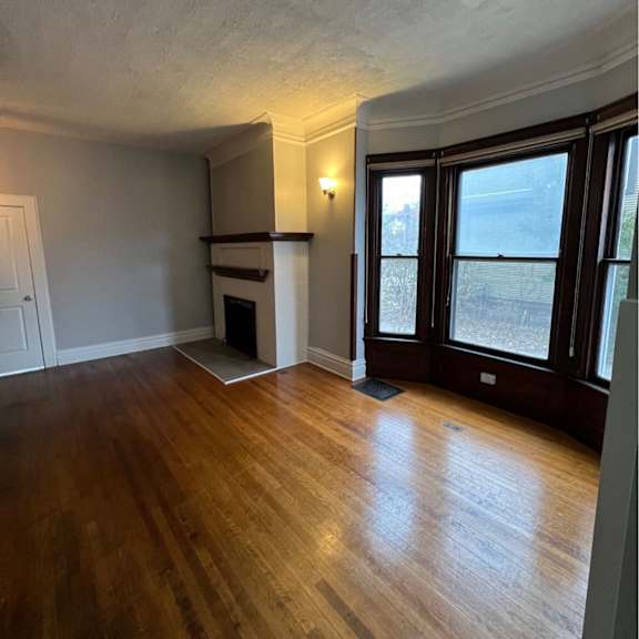 a room with wooden floors and a window overlooking a snowy landscape.