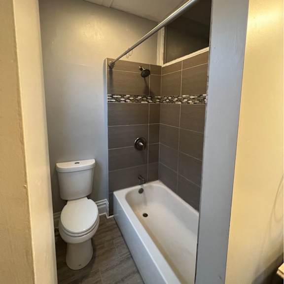 a white toilet sits next to a bathtub in a bathroom.