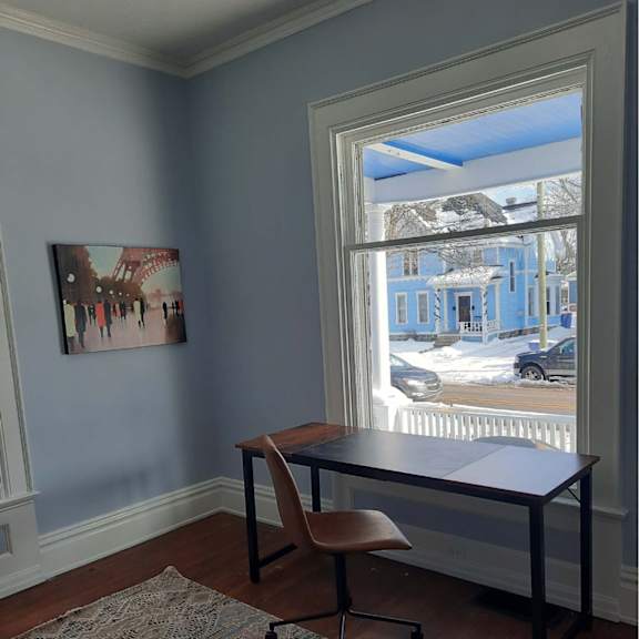a room with a desk and chair in front of a window.
