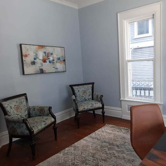a room with a table, two chairs and two pictures on the wall.