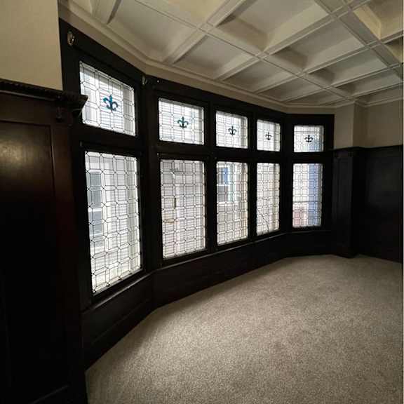 a room with a carpeted floor and a wall with a row of windows.