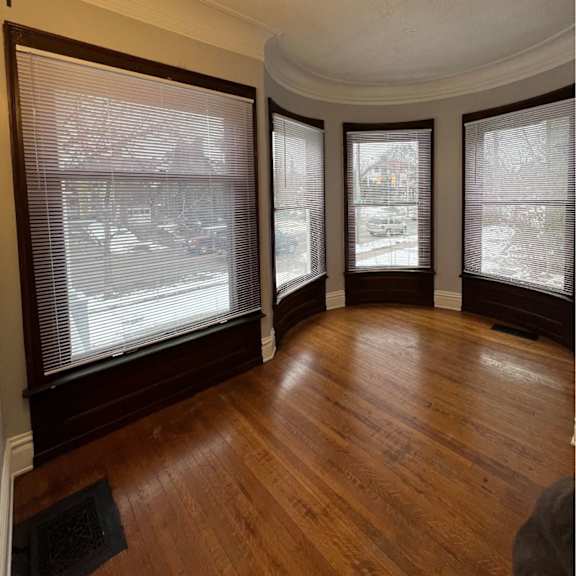 a room with wood floors and three windows.