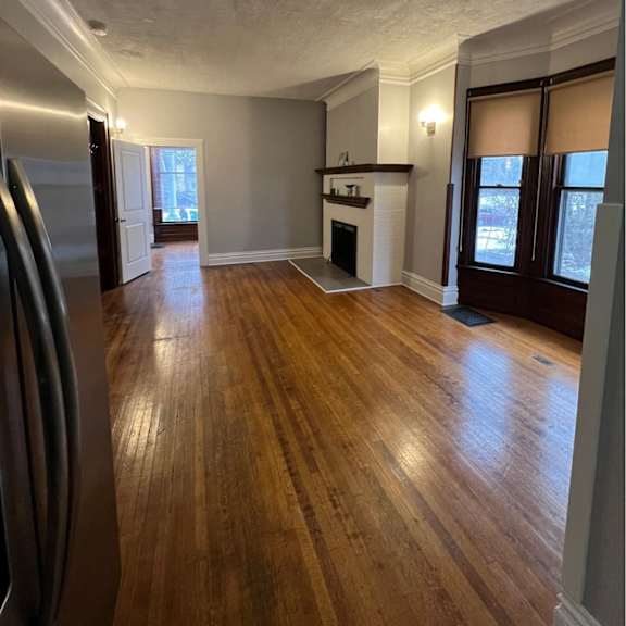 a kitchen with wood floors and a stainless steel refrigerator.