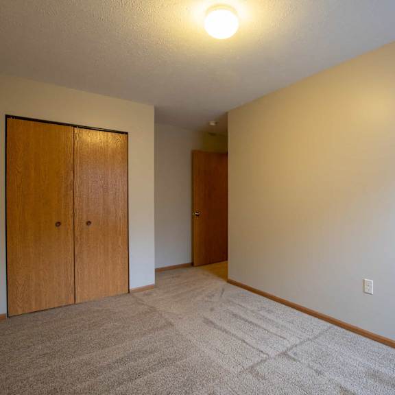 a room with a carpeted floor and two wooden doors.