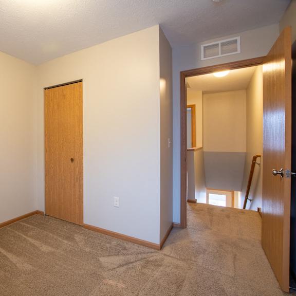 a room with a brown carpet and a wooden door.
