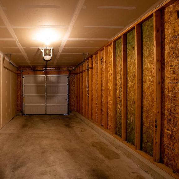 a long, narrow room with a door in the middle and wooden walls on the right side.