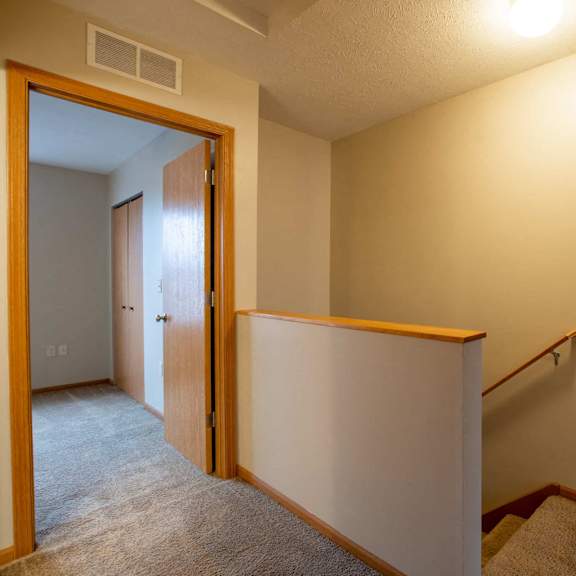a hallway with a carpeted floor and a staircase.