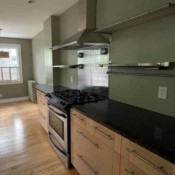 a kitchen with a stove top oven and wooden floors.