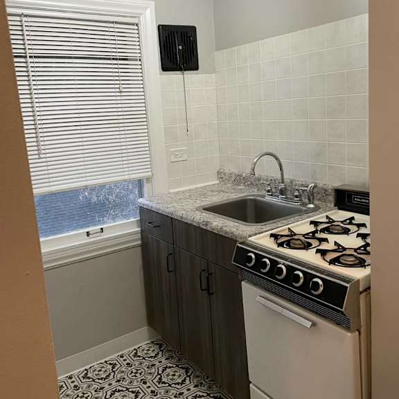 a kitchen with a white stove top oven and a black and white tiled floor.