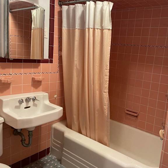 a bathroom with a pink tiled wall and a white sink.