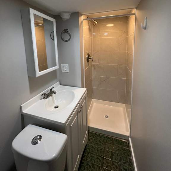a bathroom with a toilet, sink, mirror, and shower.