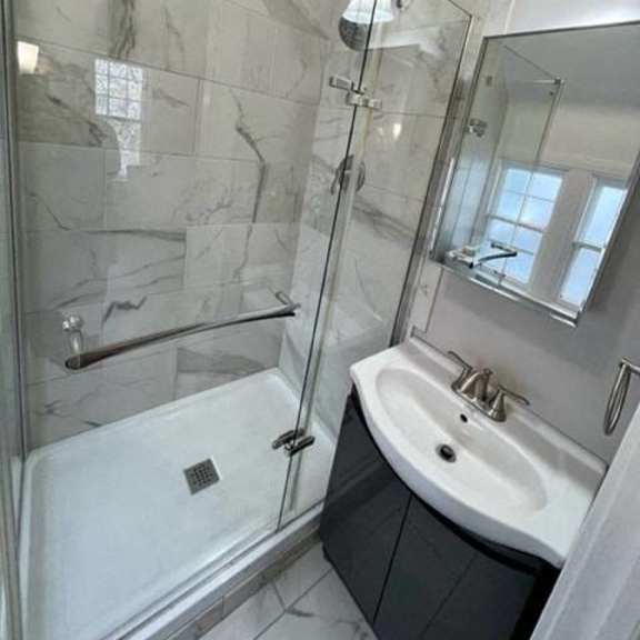a bathroom with a marble tile wall and a white sink.