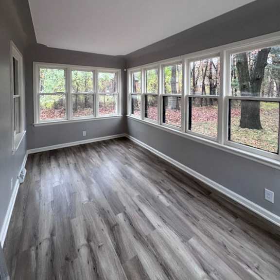 a room with wooden floors and large windows overlooking a tree.