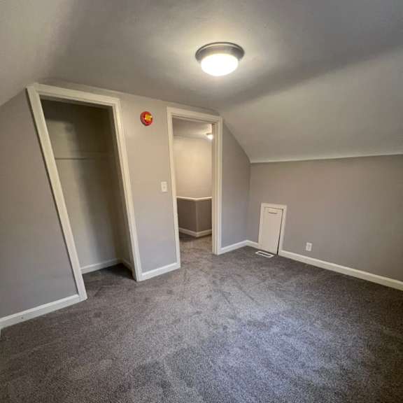 a room with a grey carpet and a white door with a red sign on it.