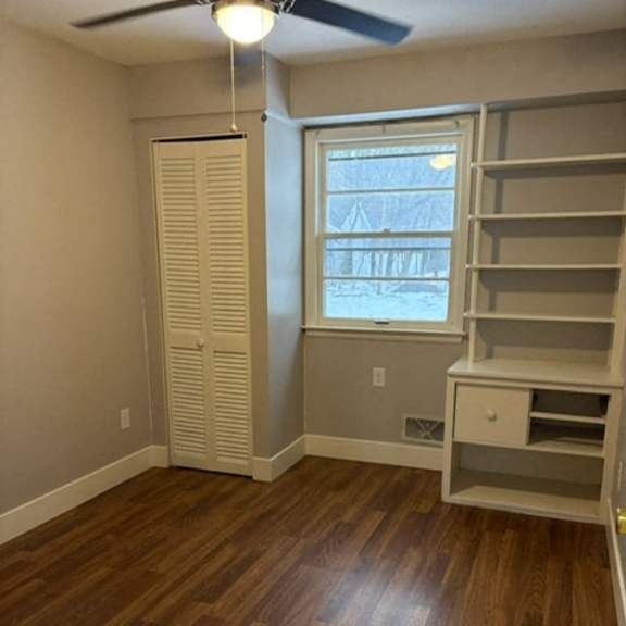 a room with wooden floors and a window with blinds.