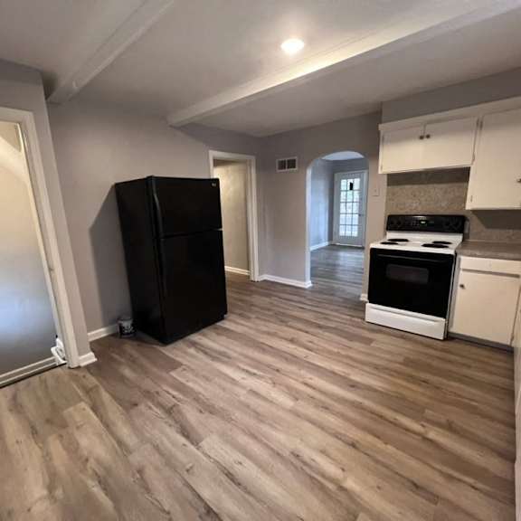 a kitchen with a black fridge, white cabinets, and a stove top oven.