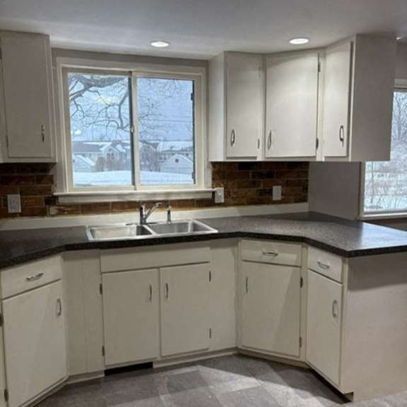a kitchen with white cabinets and a black countertop.