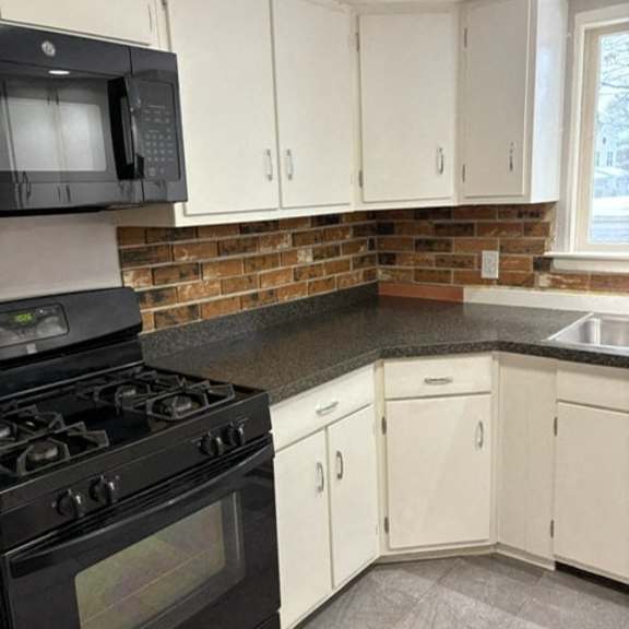 a kitchen with a black stove and white cabinets.