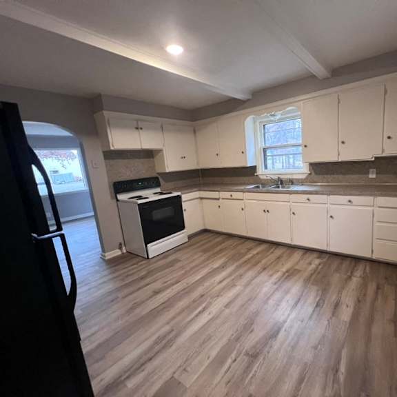 a kitchen with white cabinets and a black refrigerator.