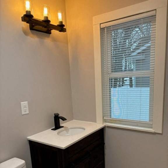 a bathroom with a sink, toilet and window.