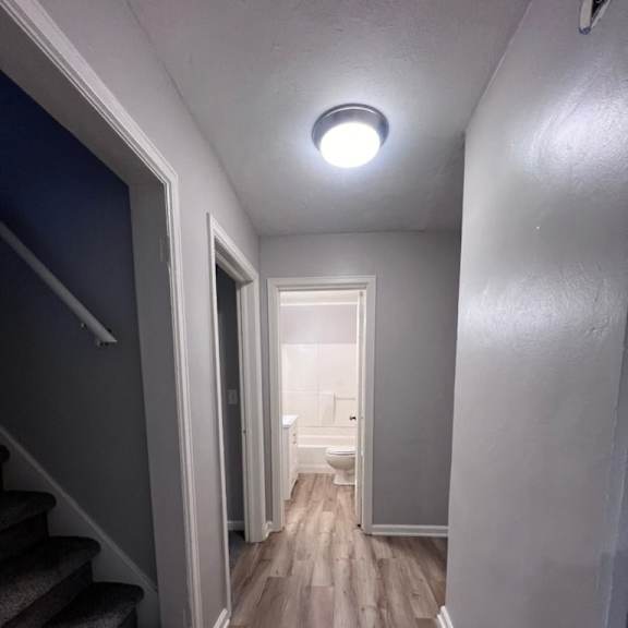 a hallway with a staircase on the left and a door on the right.