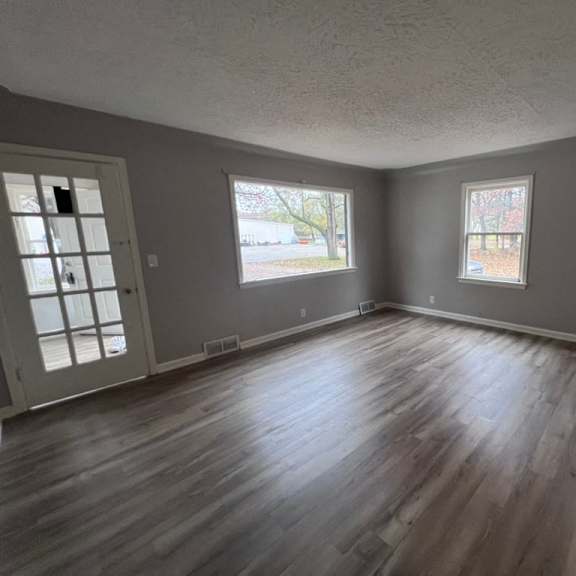 a room with wooden floors and two windows.