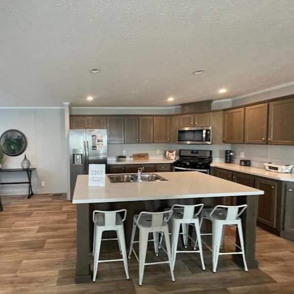 a kitchen with a white island and white chairs.