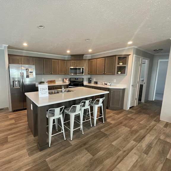 a kitchen with a white island and white chairs.