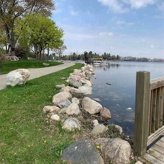 a wooden dock extends into a lake with rocks on the shore.