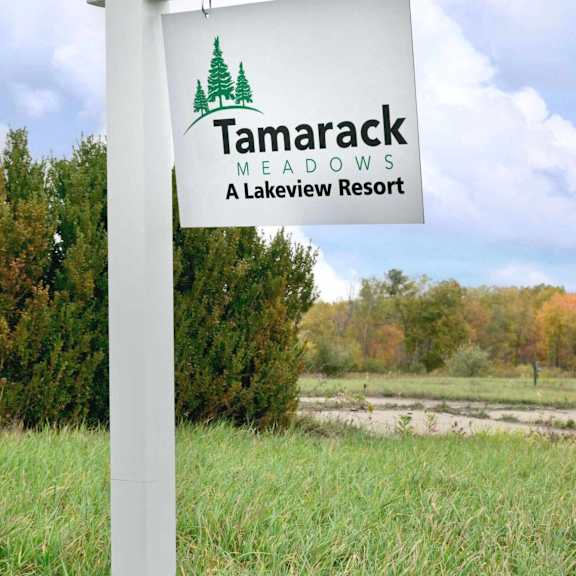 a sign for tamarack meadows lakeview resort stands in a grassy field.