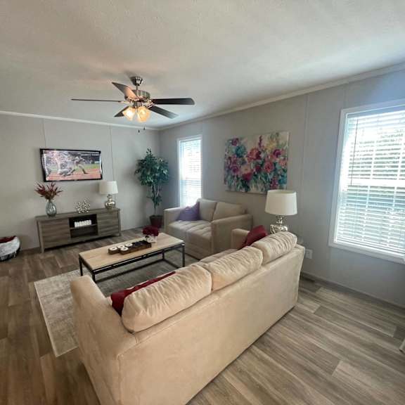 a living room with a beige couch, a coffee table, and a ceiling fan.